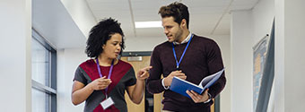 lecturers talking in hallway, holding papers
